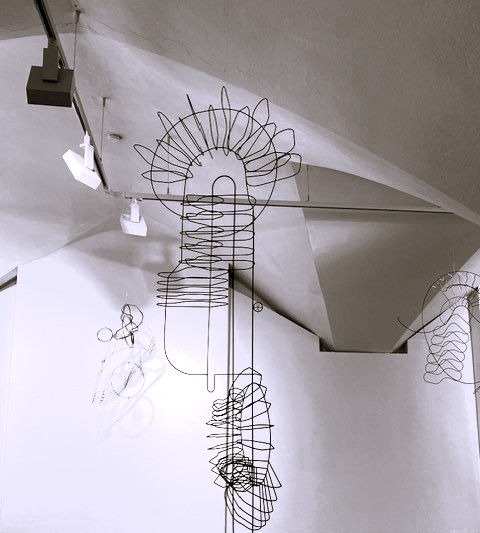 Drahtskulptur von Constantin Luser, frei im Raum hängend, beleuchtet in einer Galerie. Foto: Christa Linossi.